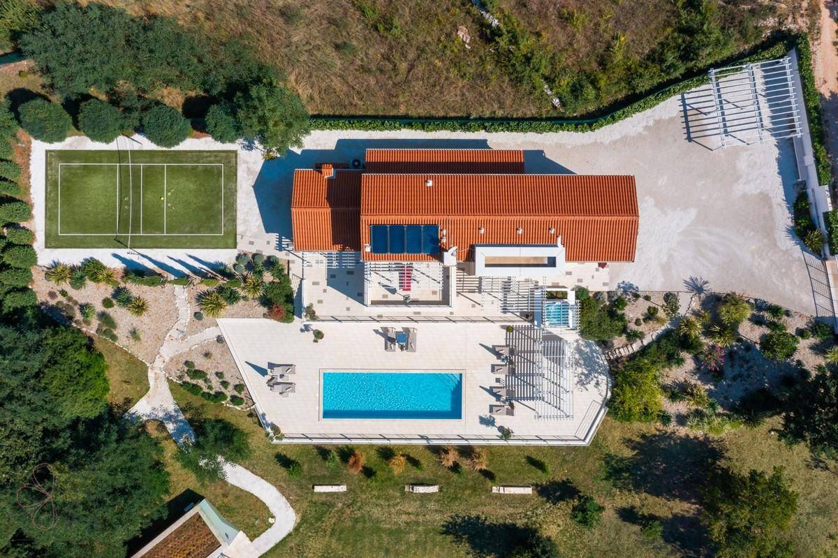 Luftaufnahme der weitläufigen Villa mit Pool, Tennisplatz und gepflegter Gartenanlage.