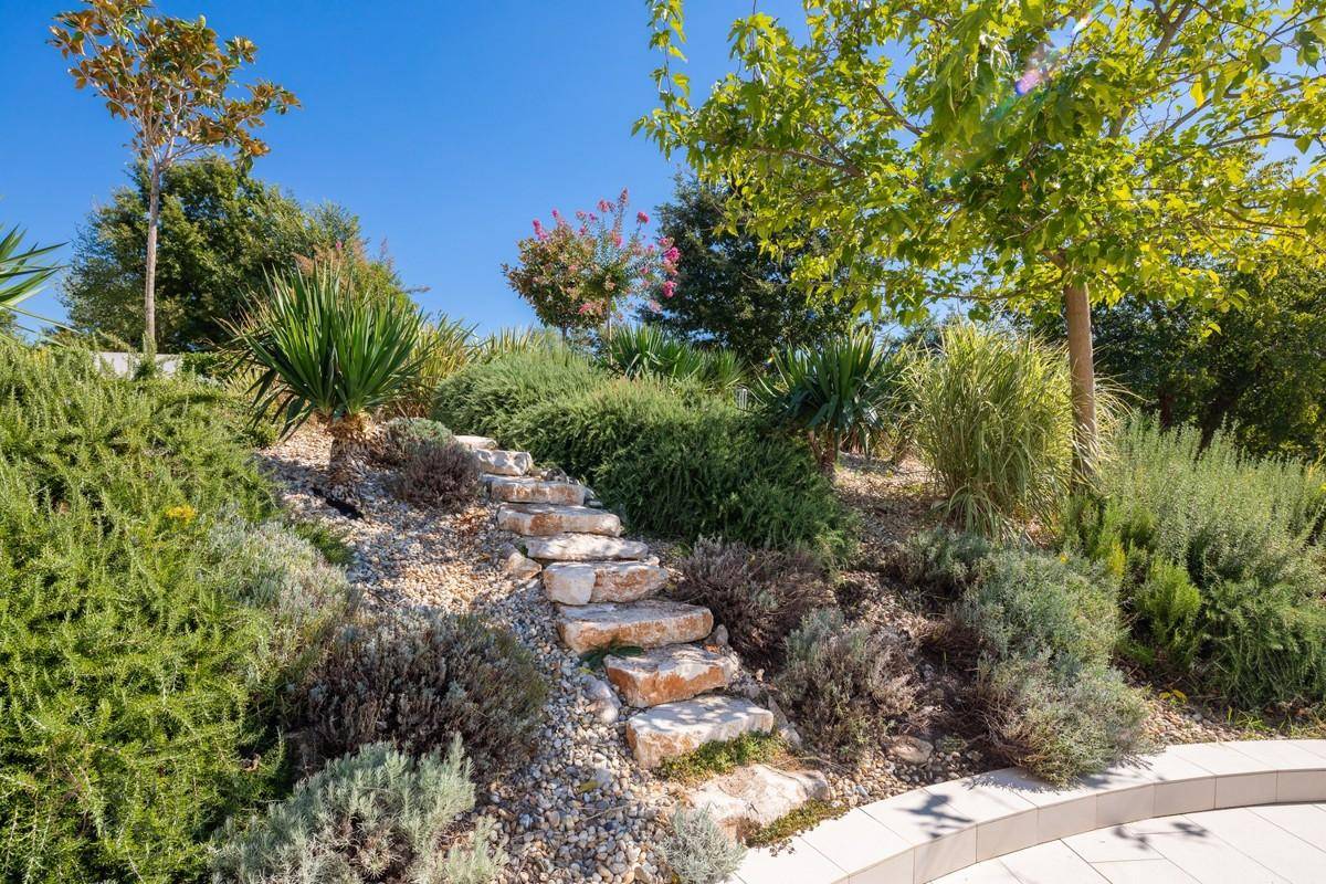 Mediterraner Steingarten mit üppiger Bepflanzung und Natursteintreppe.