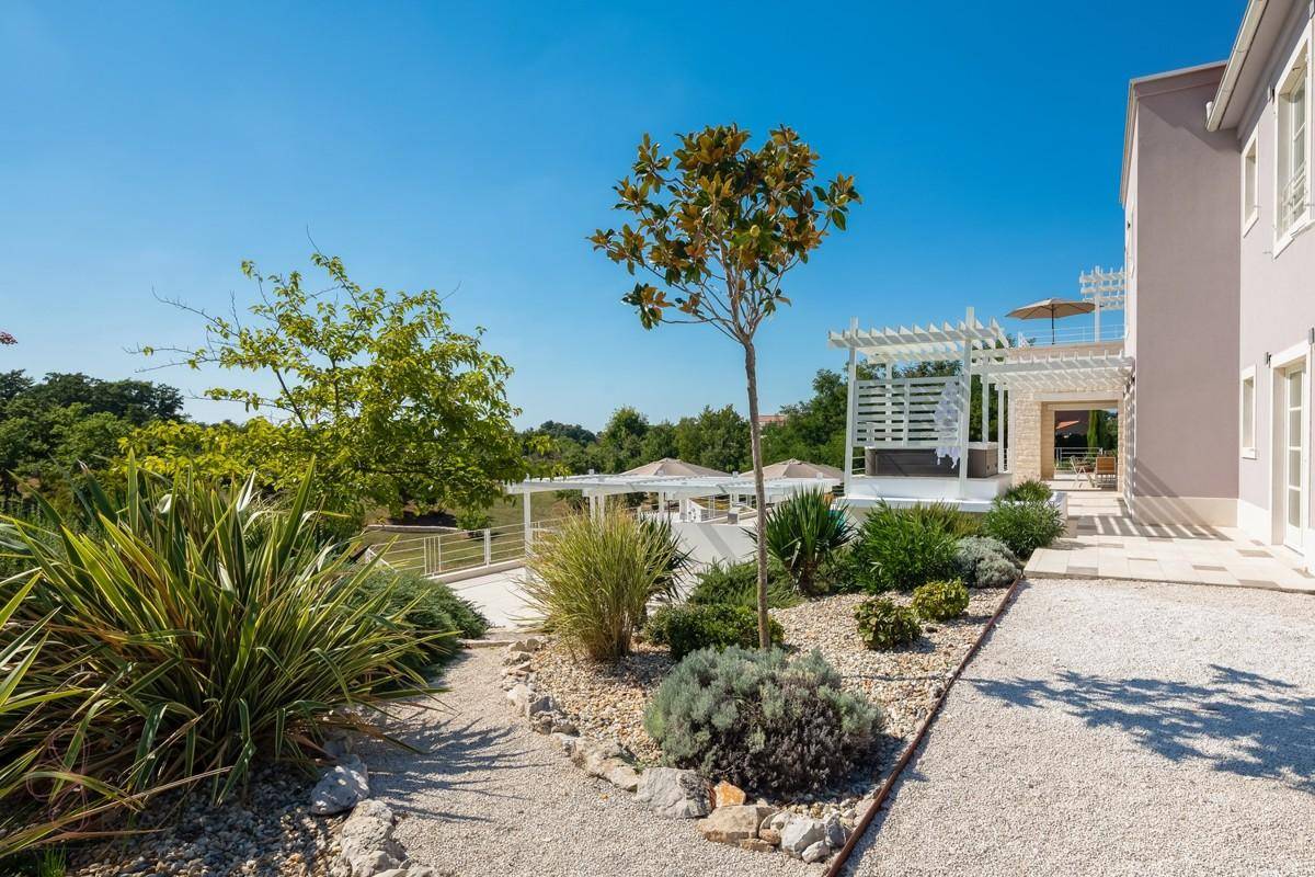 Gepflegter Gartenbereich mit Kieswegen und mediterranen Pflanzen neben der Villa.