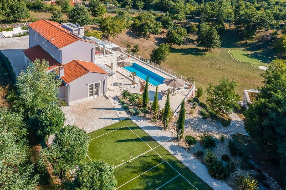 Luftaufnahme der luxuriösen Villa mit Tennisplatz, Pool und weitläufigem Grundstück.