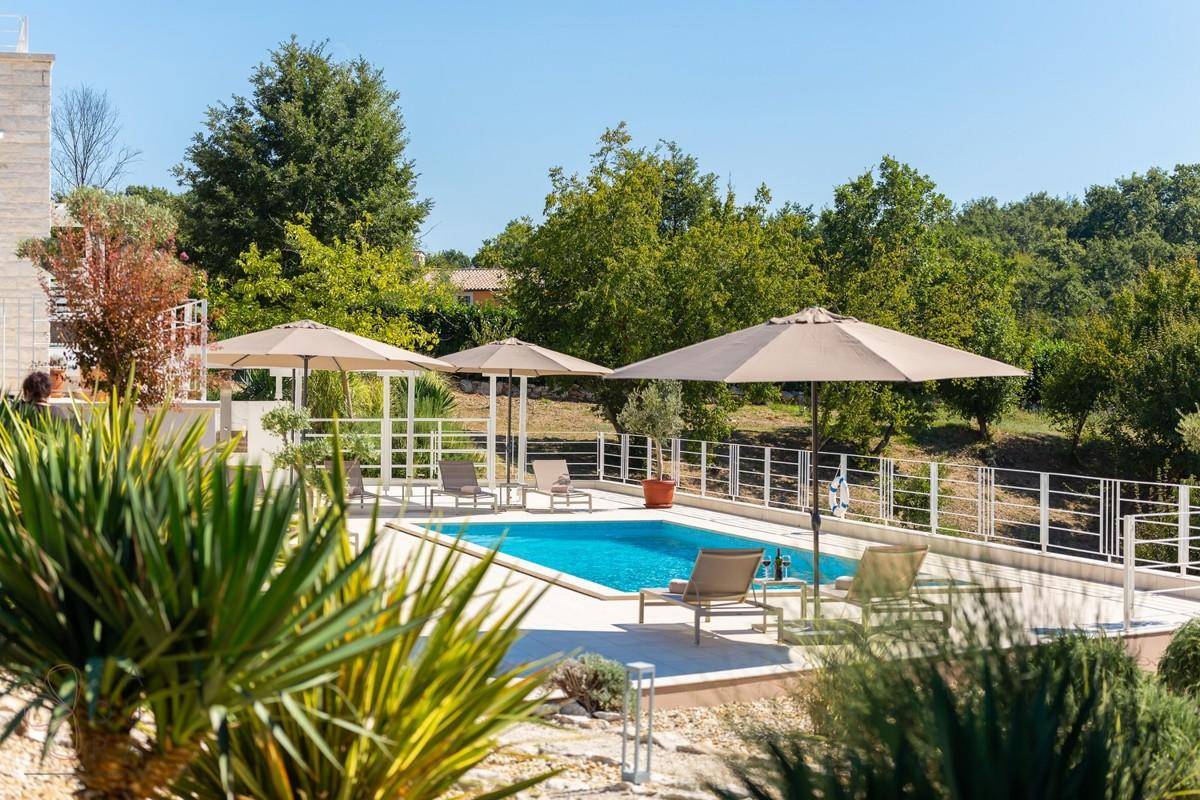 Erfrischender Poolbereich umgeben von mediterraner Bepflanzung unter blauem Himmel.