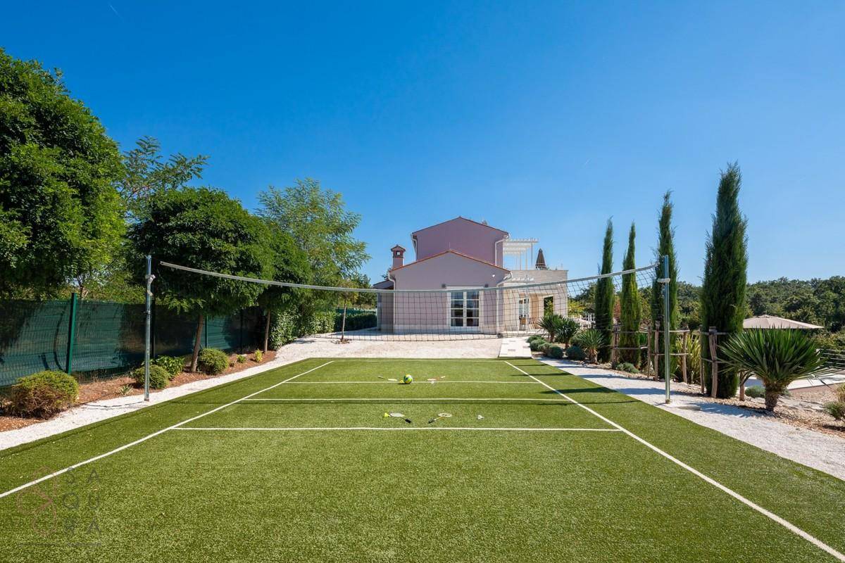 Gepflegter Tennisplatz mit Netz und Ball, bereit für ein Spiel unter freiem Himmel.