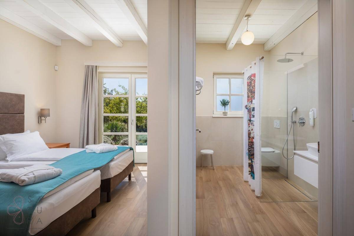 Schlafzimmer mit zwei Einzelbetten und direktem Zugang zum modernen Badezimmer.