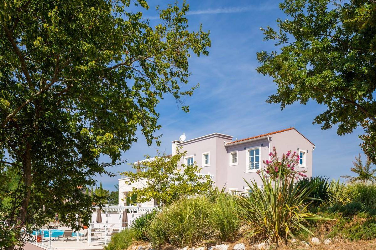 Moderne Villa eingebettet in eine grüne Landschaft mit altem Baumbestand.