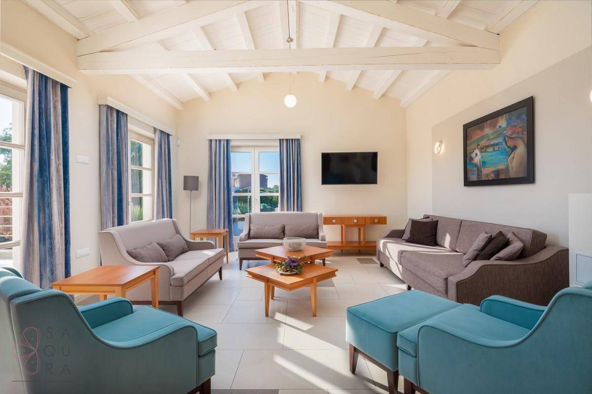 Geräumiges Wohnzimmer mit Holzbalkendecke, großen Fenstern und moderner Einrichtung.