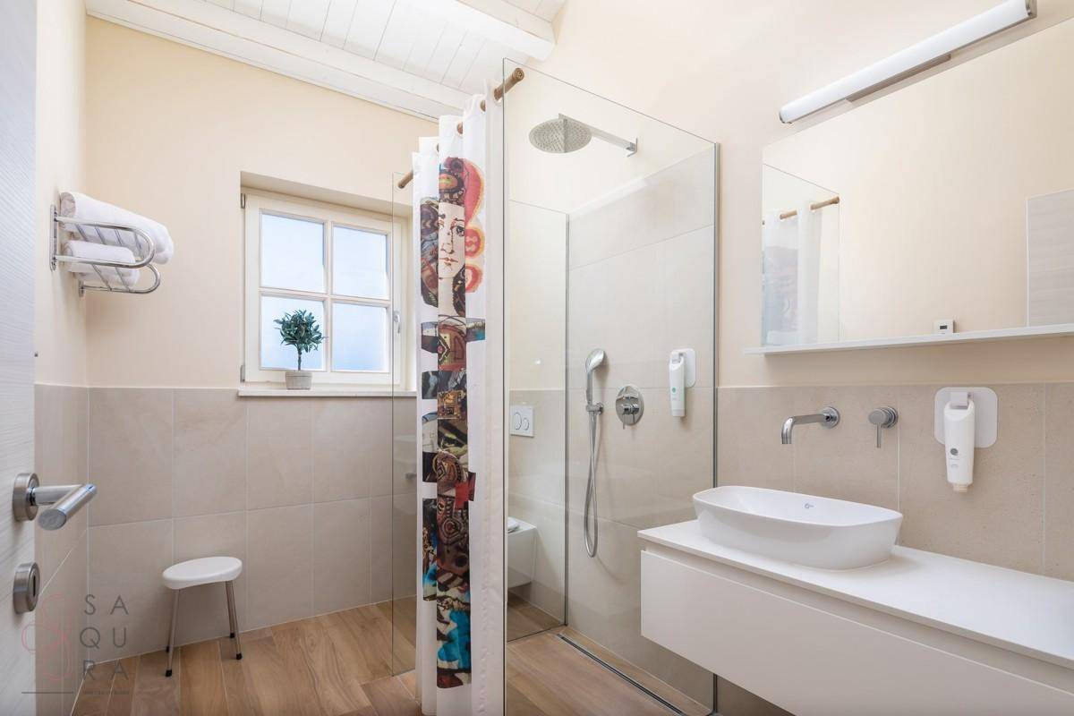 Modernes Badezimmer mit ebenerdiger Dusche, Waschbecken und Fenster für Tageslicht.