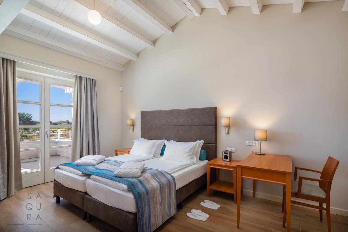 Geräumiges Schlafzimmer mit zwei Einzelbetten, Holzbalkendecke und Zugang zur Terrasse.