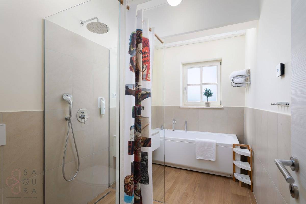 Modernes Badezimmer mit Badewanne, separater Dusche und einem Fenster für natürliches Licht.