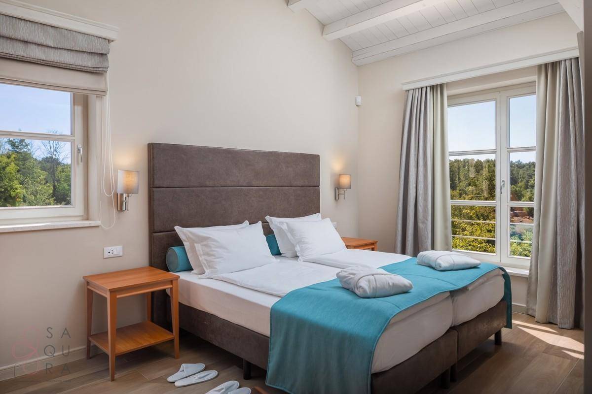 Komfortables Schlafzimmer mit Doppelbett und zwei Fenstern, die einen schönen Blick ins Grüne bieten.