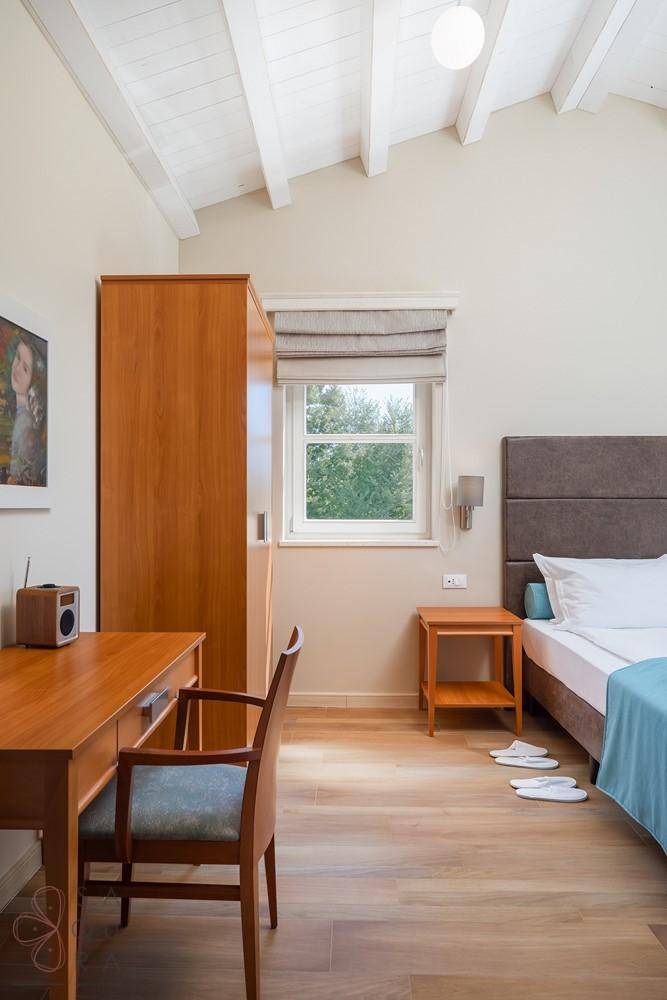 Gemütliches Schlafzimmer mit Schreibtisch, Kleiderschrank und einem Fenster mit Blick ins Grüne.