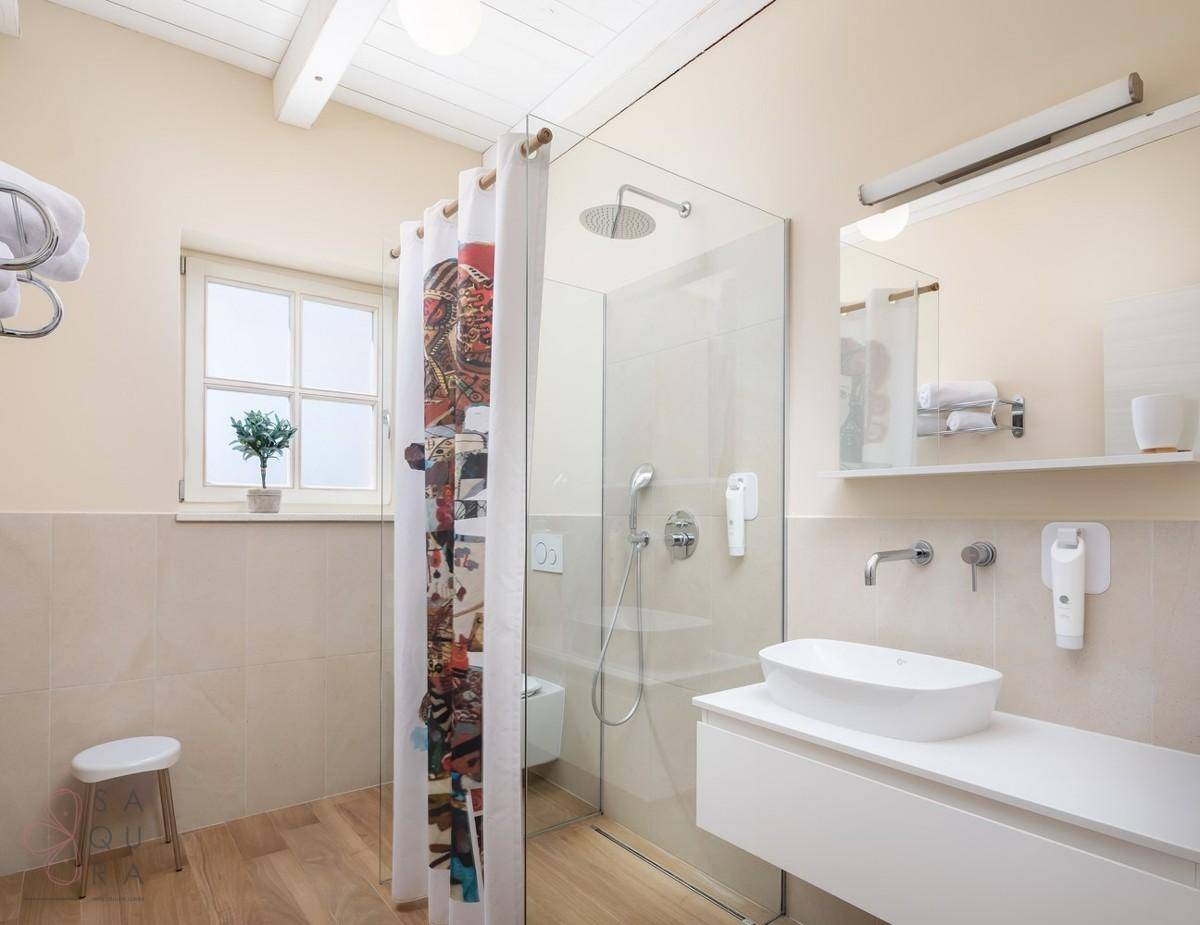 Modernes Badezimmer mit begehbarer Dusche, elegantem Waschbecken und einem Fenster für Tageslicht.