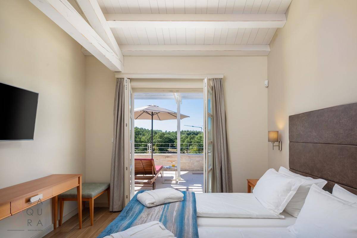 Helles Schlafzimmer mit Zugang zu einer Terrasse, ausgestattet mit einem bequemen Bett und einem Schreibtisch.