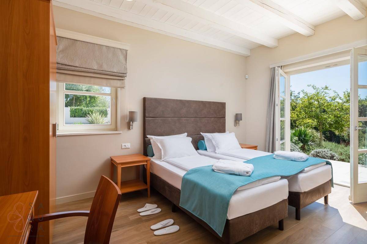 Helles Schlafzimmer mit zwei Einzelbetten, Holzboden und Blick ins Grüne.