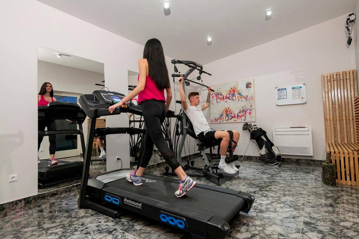 Gut ausgestatteter Fitnessraum mit Laufband und Kraftgeräten, ideal für das tägliche Training.