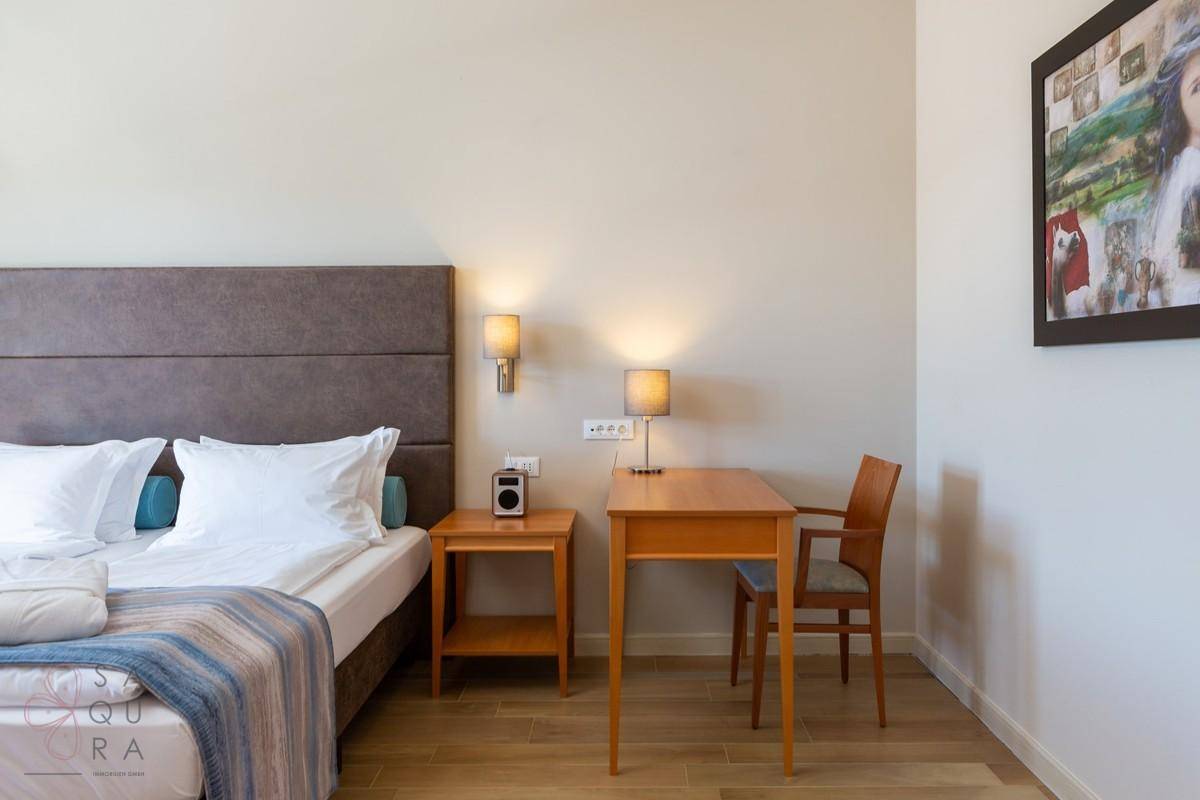Gemütliches Schlafzimmer mit Doppelbett, Schreibtisch und Holzboden, ideal für entspannte Nächte.