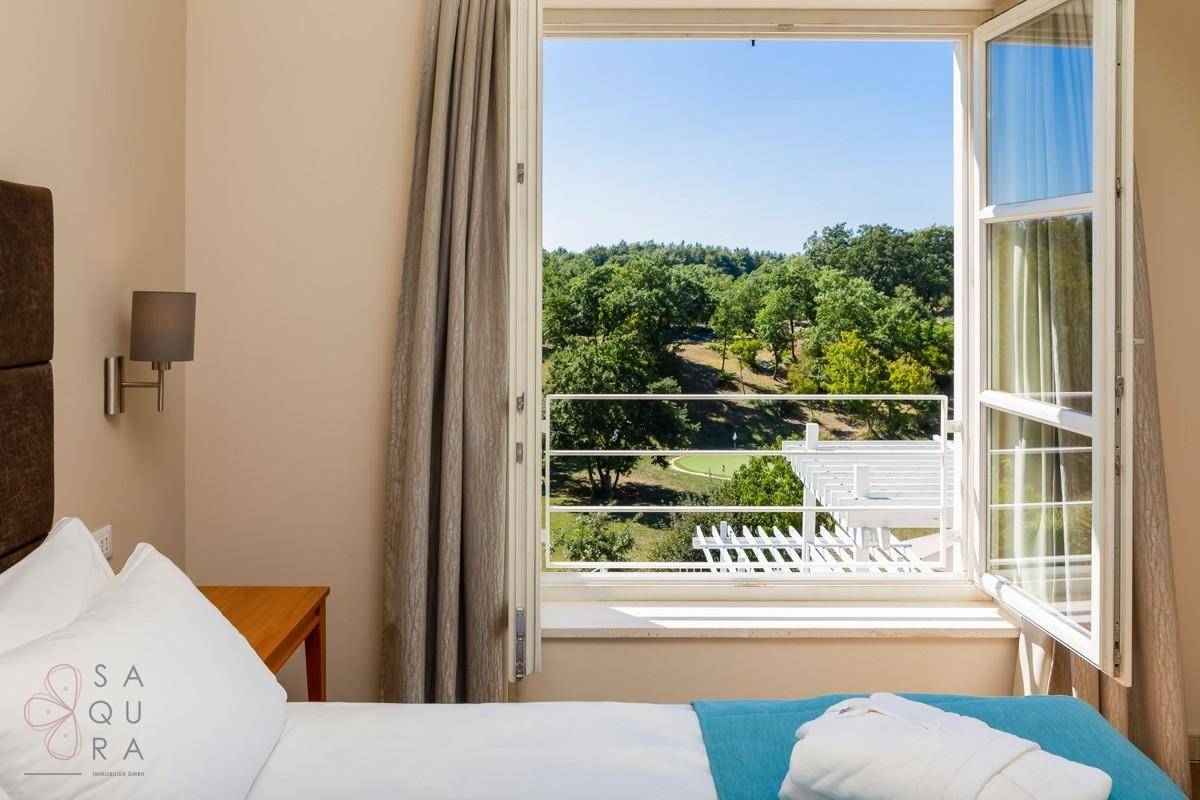 Malerischer Ausblick aus dem Schlafzimmerfenster auf eine weitläufige Golfanlage und grüne Natur.