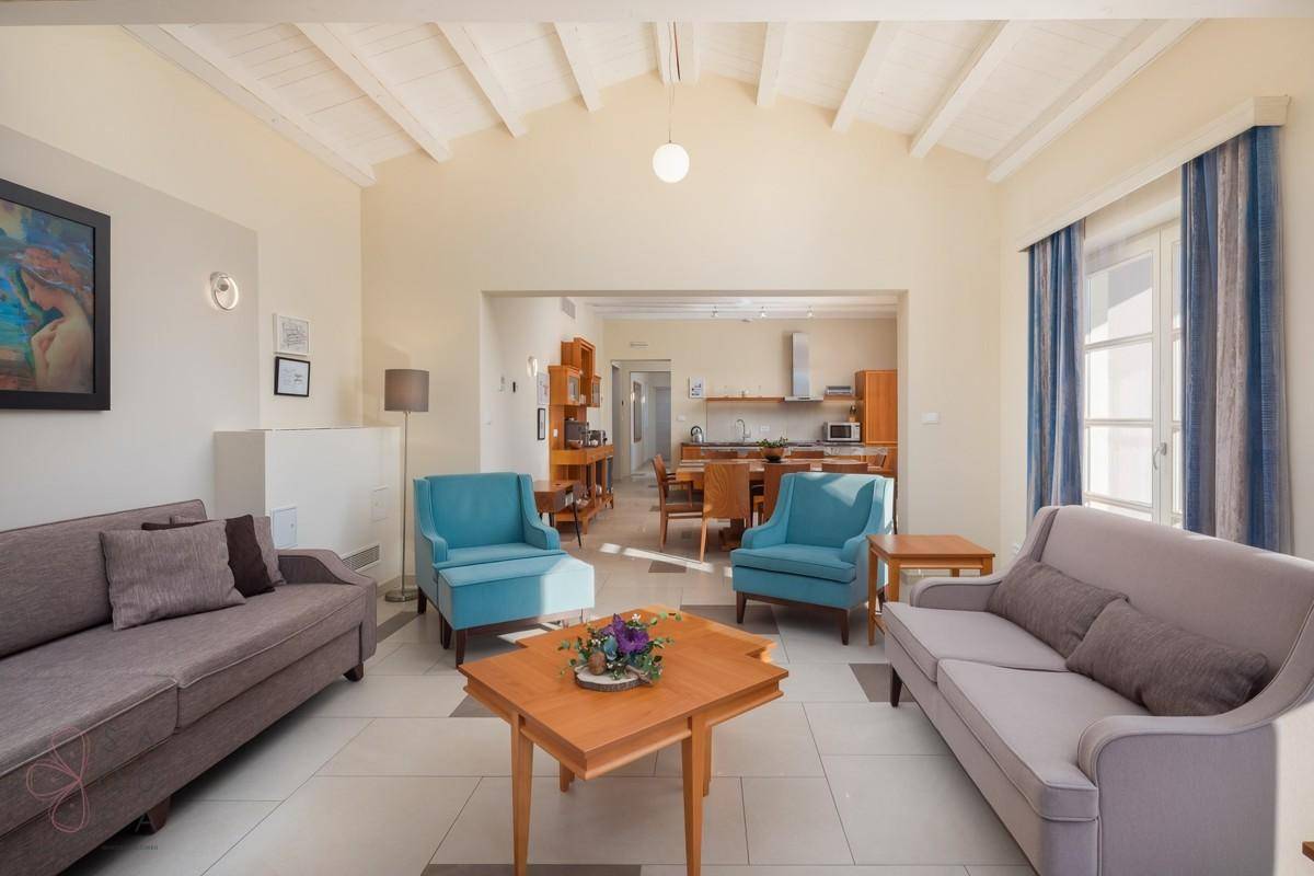 Helles Wohnzimmer mit Holzbalkendecke, bequemen Sofas und offener Verbindung zum Essbereich.