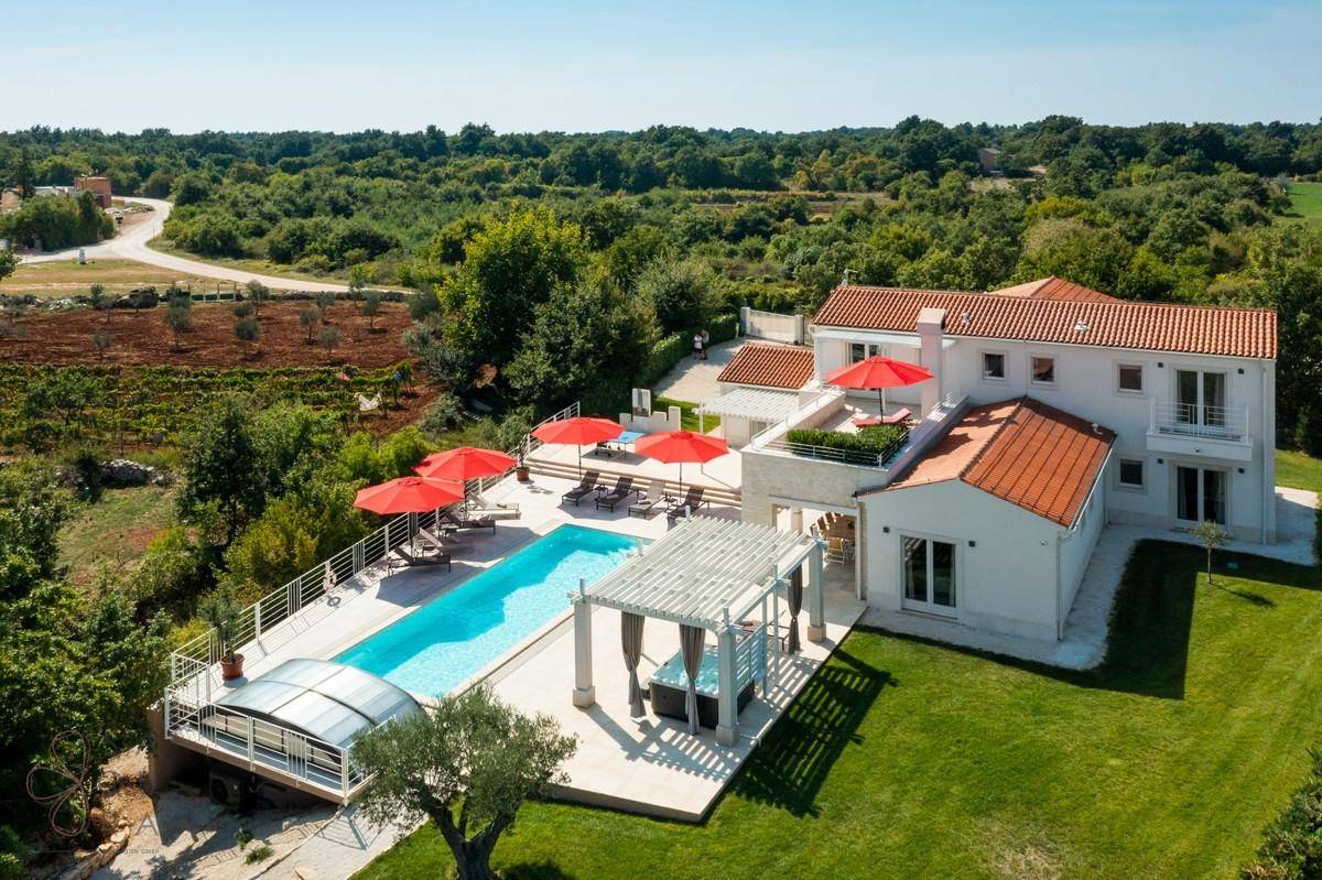 Luftaufnahme der Villa mit großem Poolbereich, umgeben von grüner Landschaft und Weinbergen.
