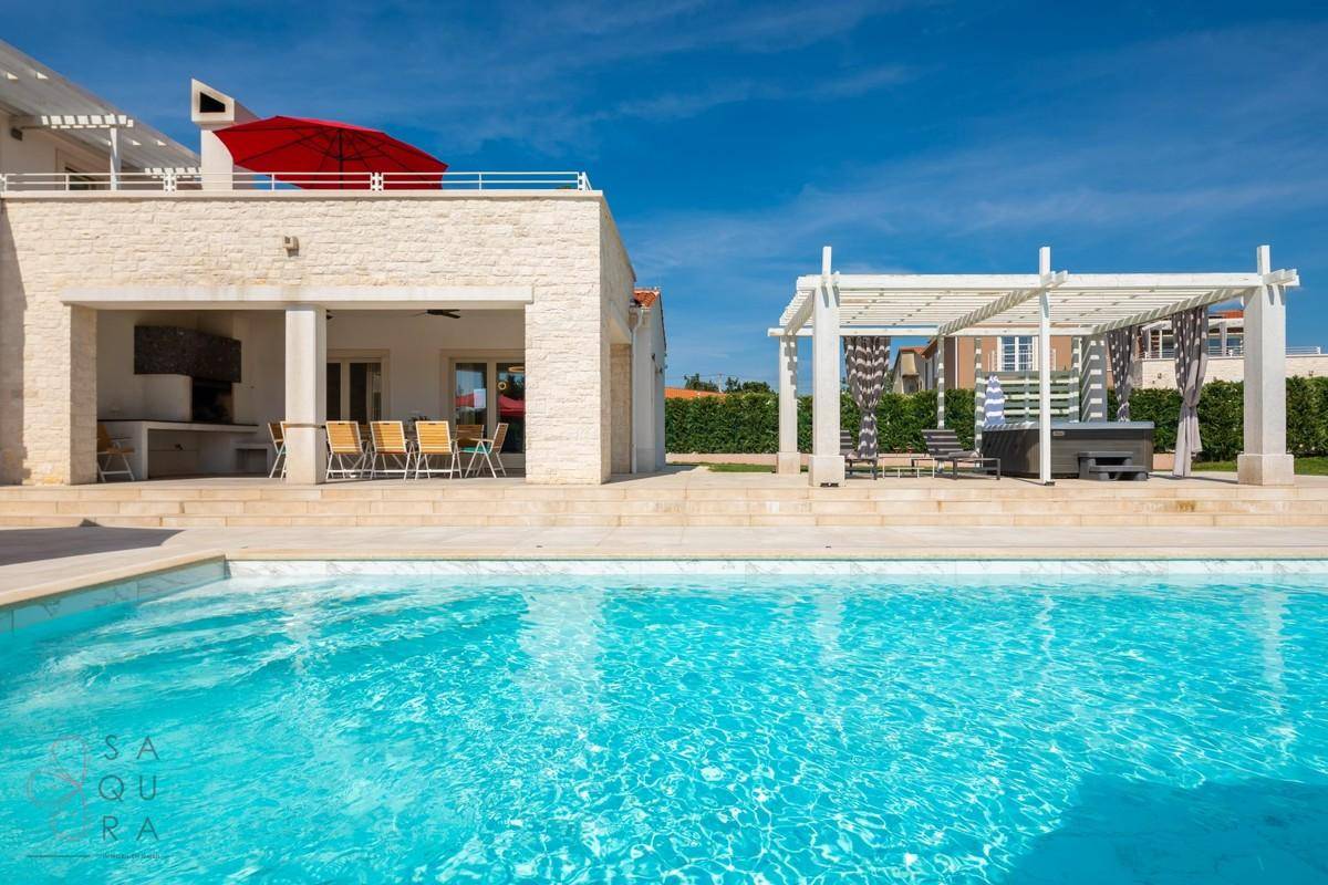 Elegante Villa mit großem Pool, überdachtem Essbereich und Whirlpool unter einer Pergola.