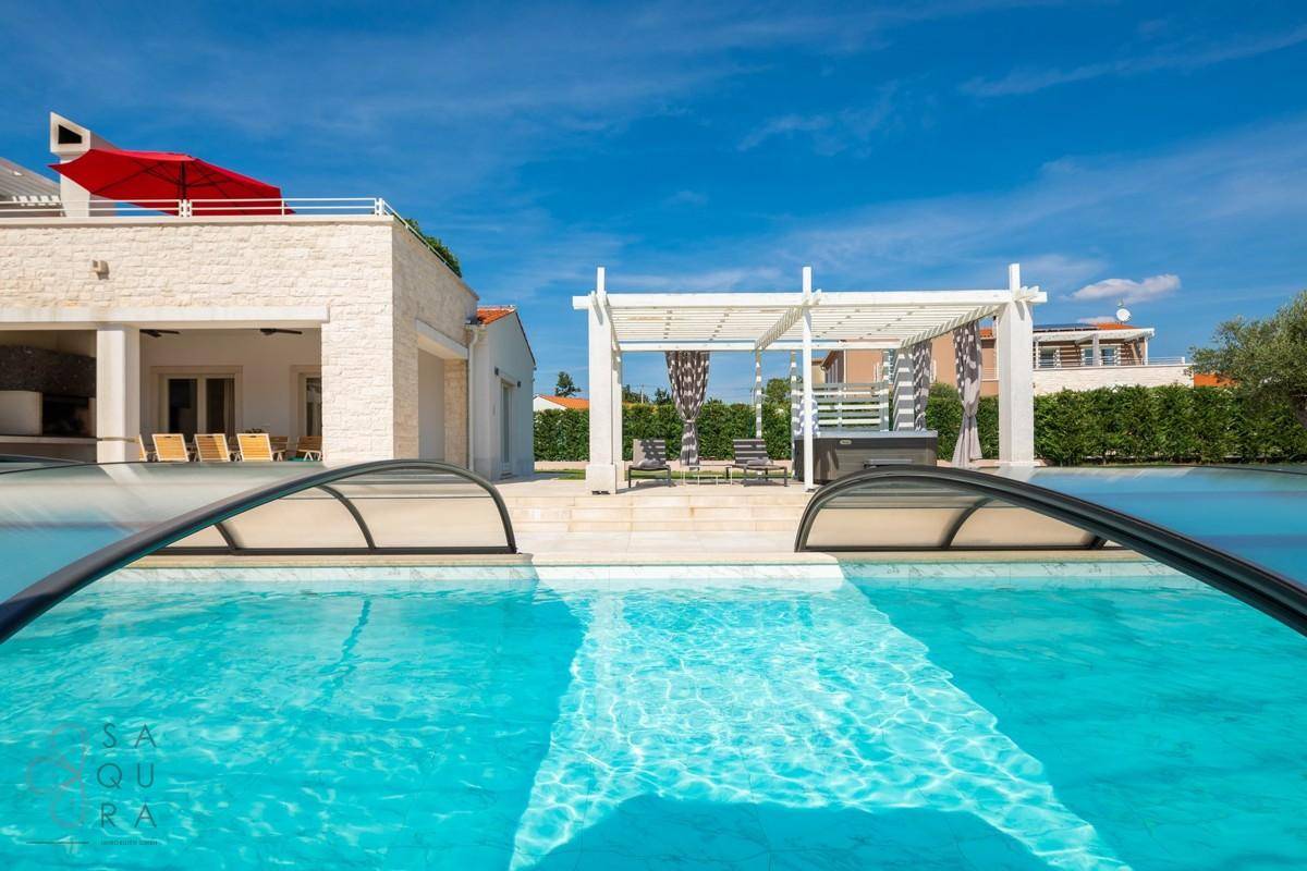 Nahaufnahme des Pools mit geöffneter transparenter Abdeckung, bereit zum Schwimmen.