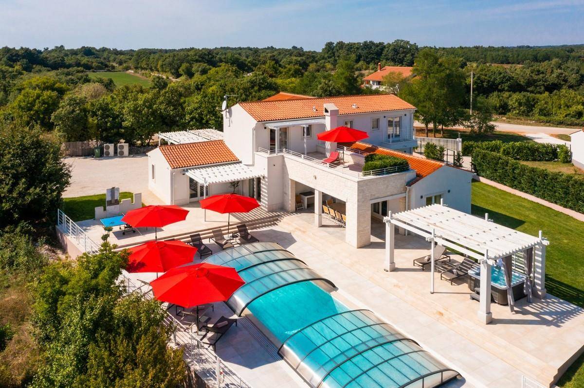 Luftaufnahme der Villa mit Poolabdeckung, umgeben von üppiger Vegetation und ländlicher Umgebung.