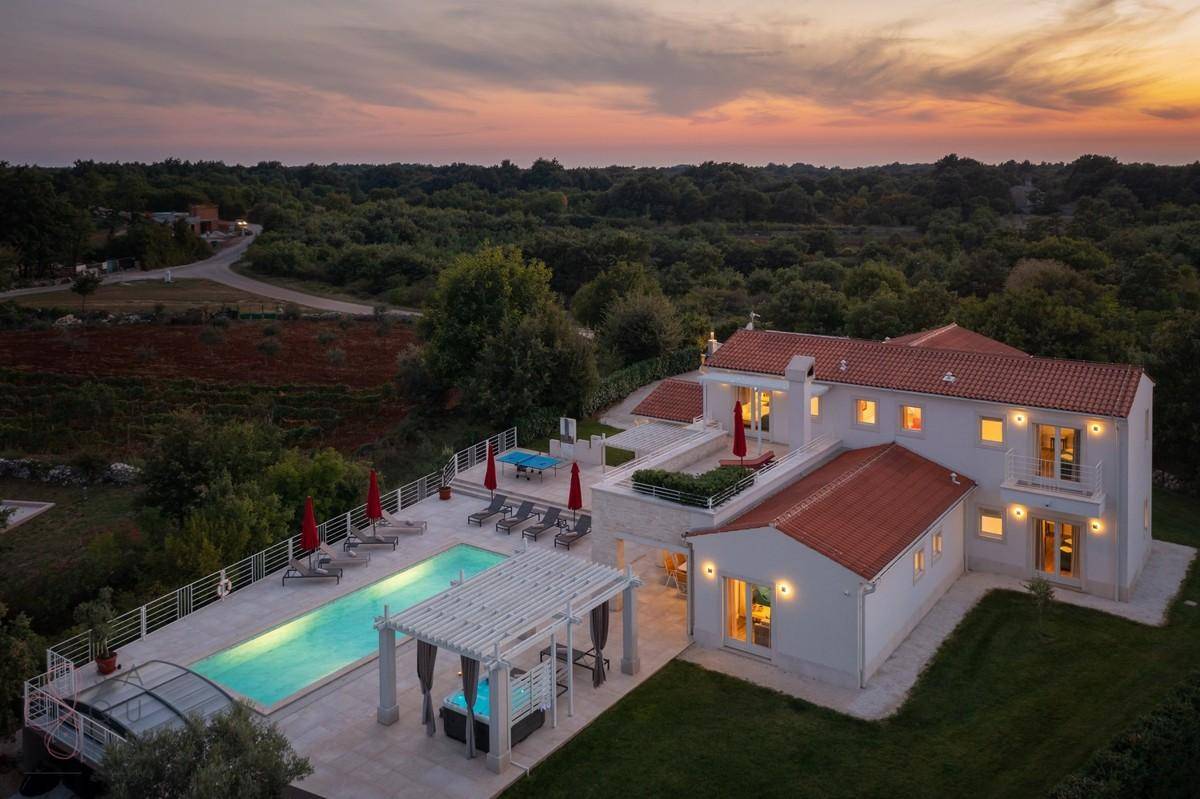 Panoramablick auf die luxuriöse Villa mit Pool, Whirlpool und weitläufigem Grundstück bei Sonnenuntergang.