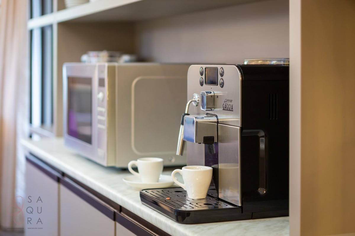 Hochwertige Kaffeemaschine und Mikrowelle auf der Küchenarbeitsplatte.