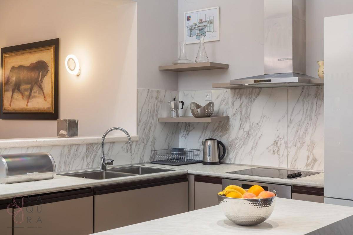 Moderne Küchenzeile mit Spüle, Induktionskochfeld und eleganten Marmor-Rückwänden.