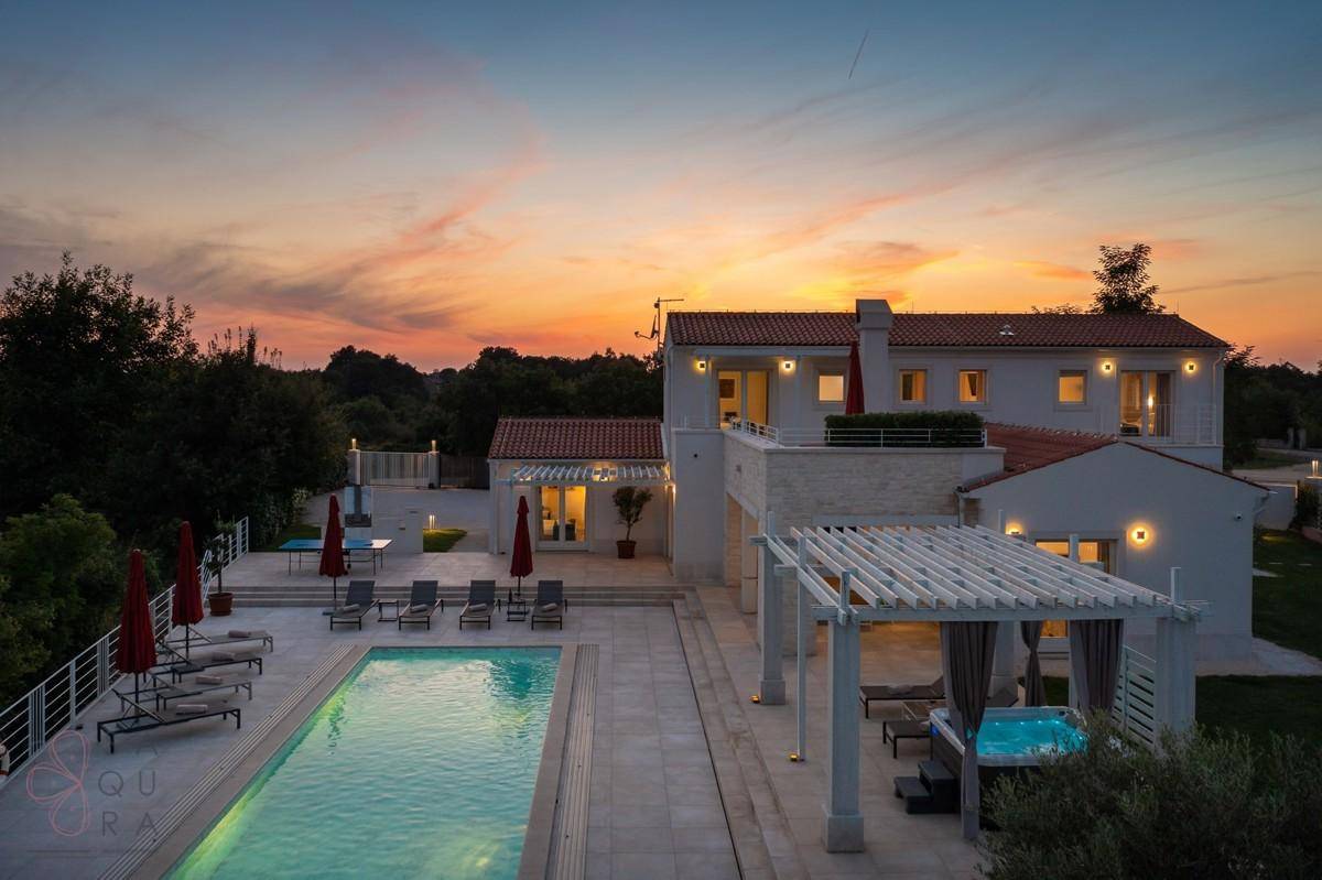 Luxuriöse Villa mit großem Pool, Whirlpool und weitläufiger Terrasse bei Sonnenuntergang.