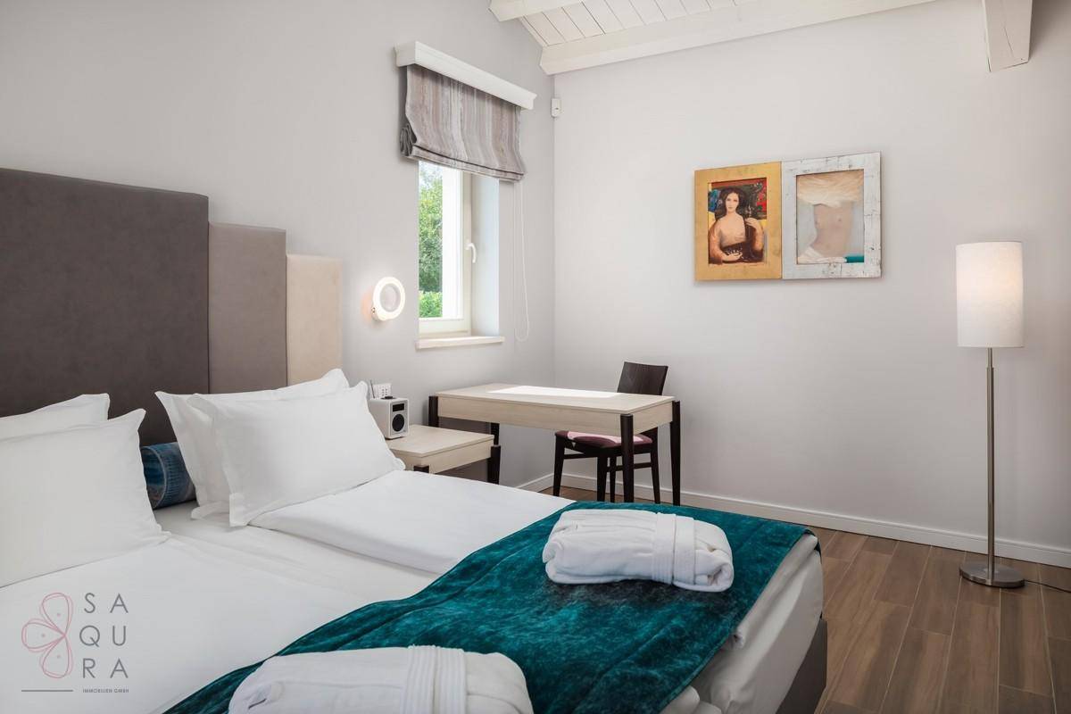 Gemütliches Schlafzimmer mit Schreibtisch, Holzbalkendecke und moderner Stehlampe.