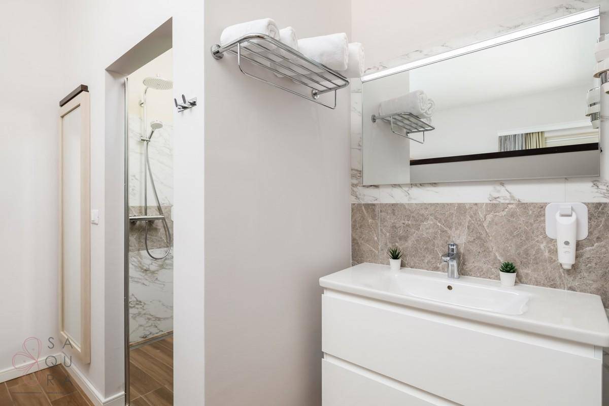 Modernes Badezimmer mit Einzelwaschbecken, großem Spiegel und einer Duschkabine.