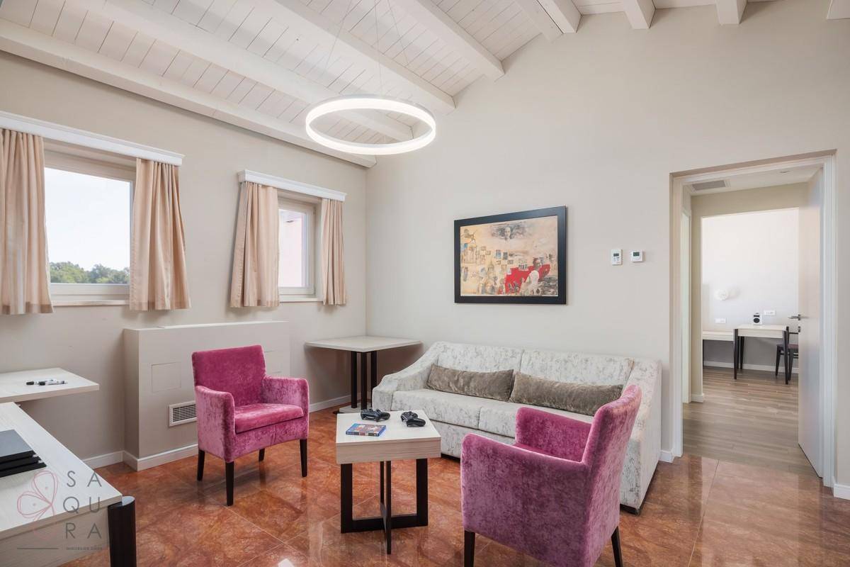Helles Wohnzimmer mit Holzbalkendecke, bequemen Sofas und moderner Deckenbeleuchtung.