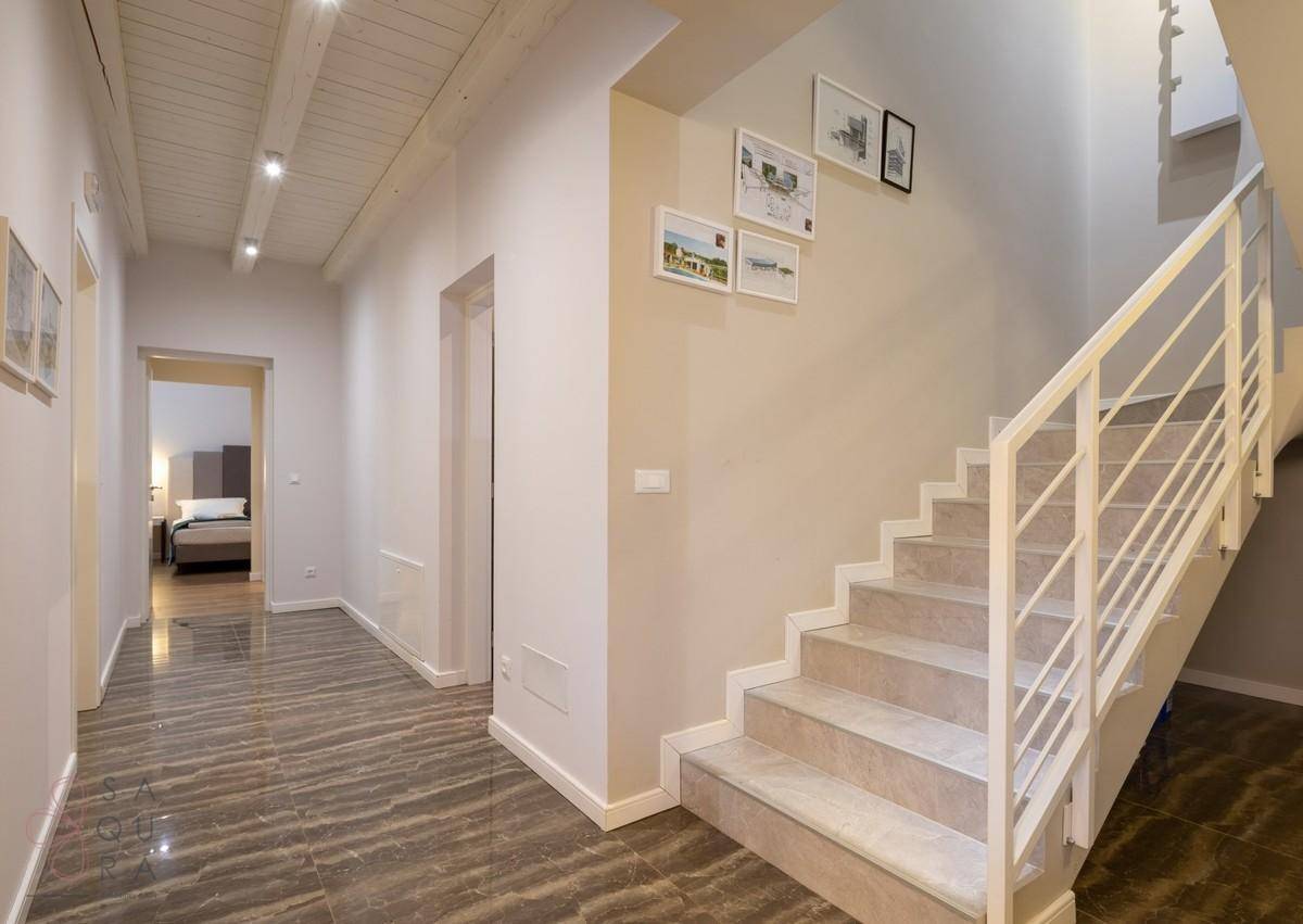 Heller Flur mit moderner Treppe, glänzenden Fliesen und Zugang zu den oberen Etagen.