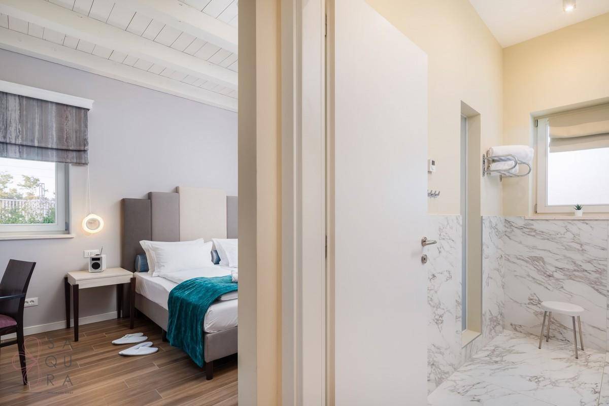 Schlafzimmer mit Holzbalkendecke und angrenzendem Badezimmer mit eleganten Marmorfliesen.