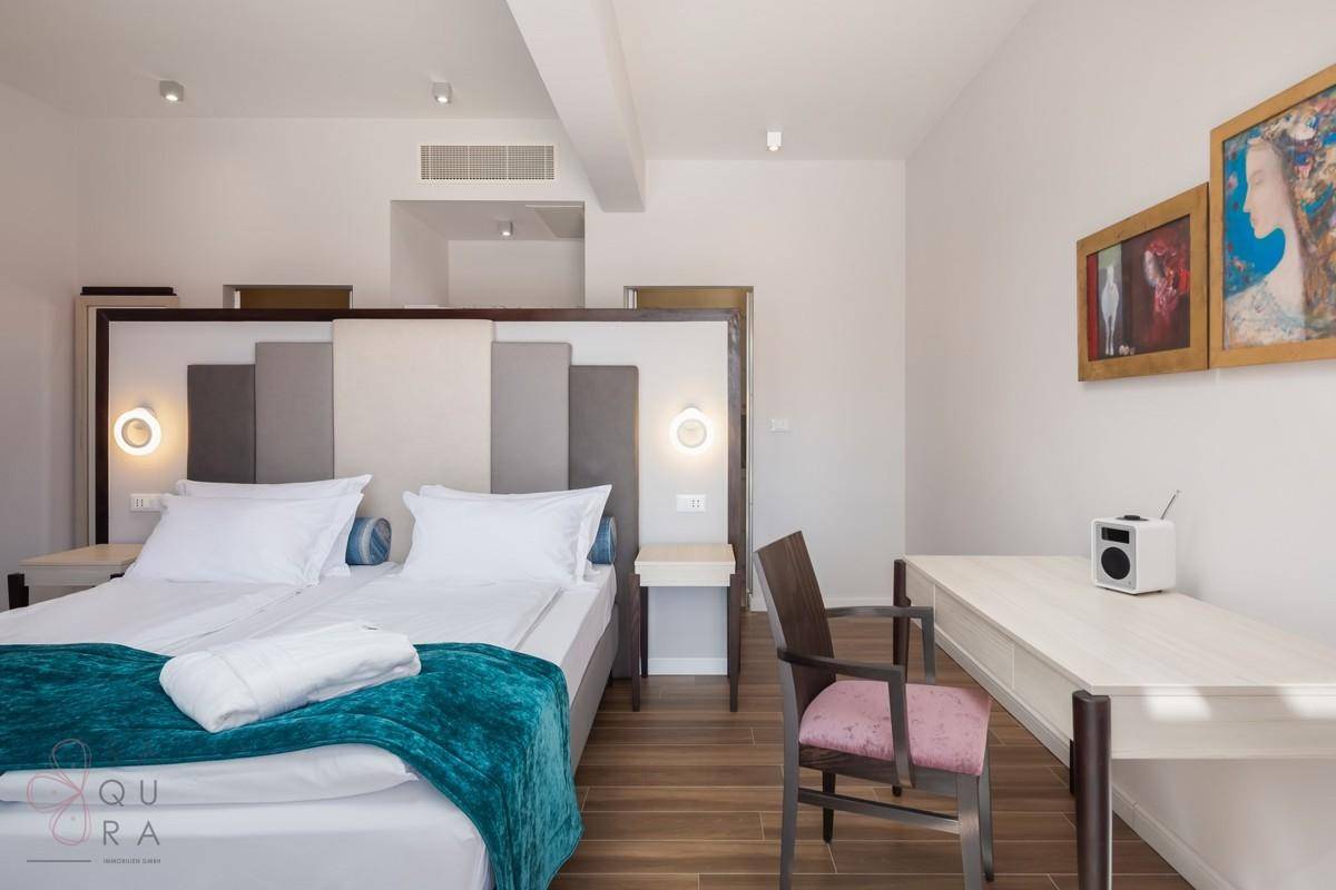 Helles Schlafzimmer mit Holzbalkendecke, zwei Einzelbetten und moderner Einrichtung.