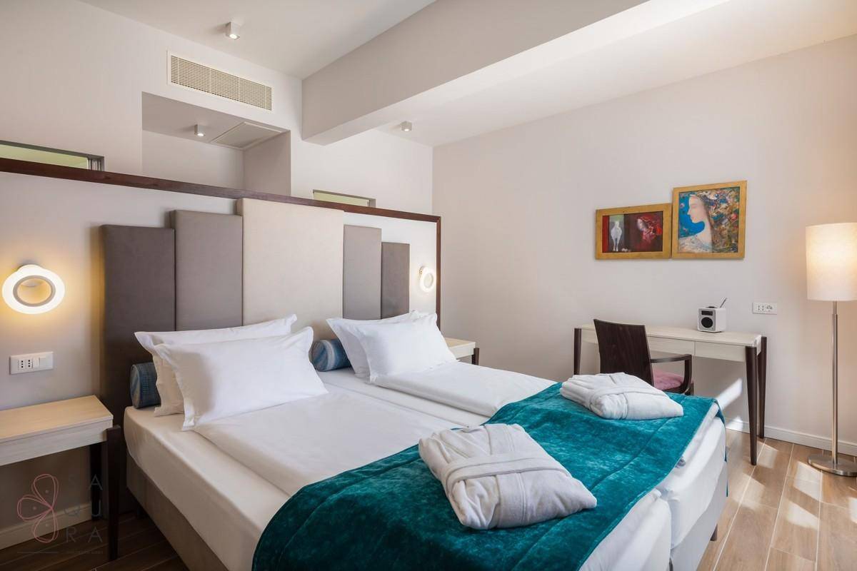 Helles Schlafzimmer mit Holzbalkendecke, zwei Einzelbetten und moderner Einrichtung.