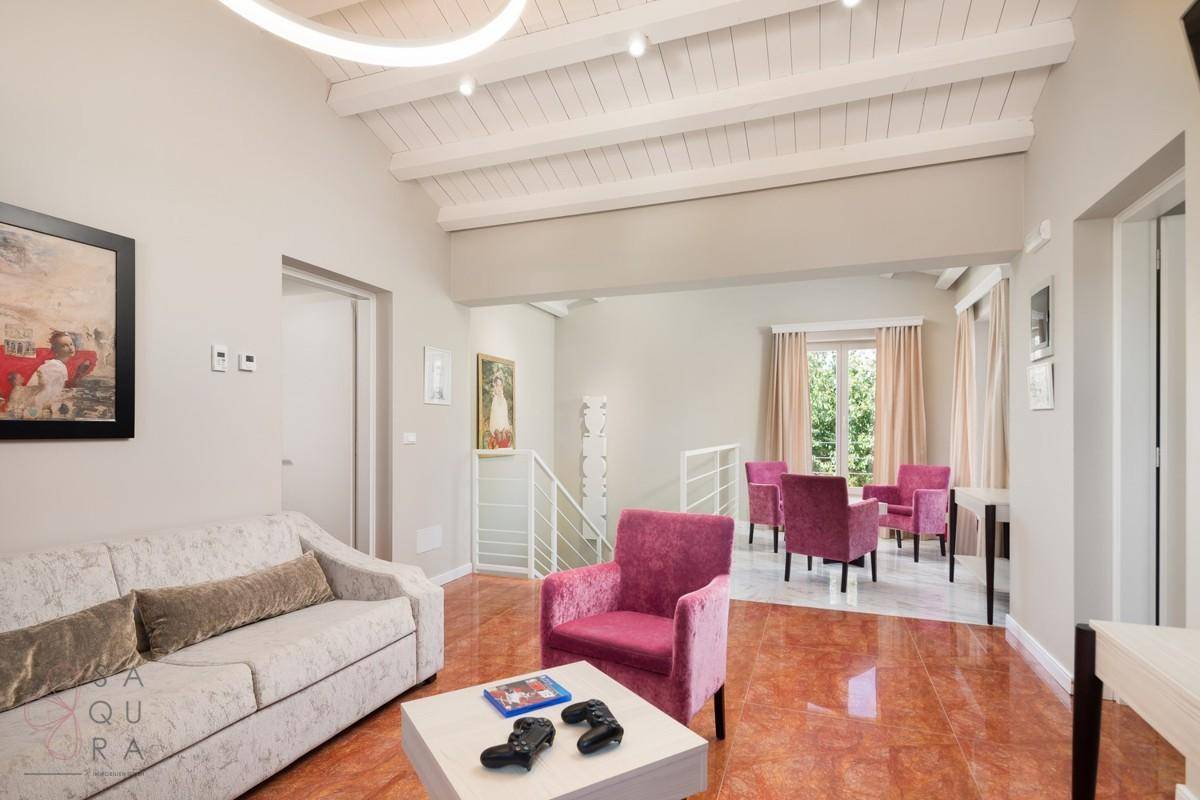Geräumiges Wohnzimmer mit Holzbalkendecke, bequemen Sofas und farbenfroher Dekoration.