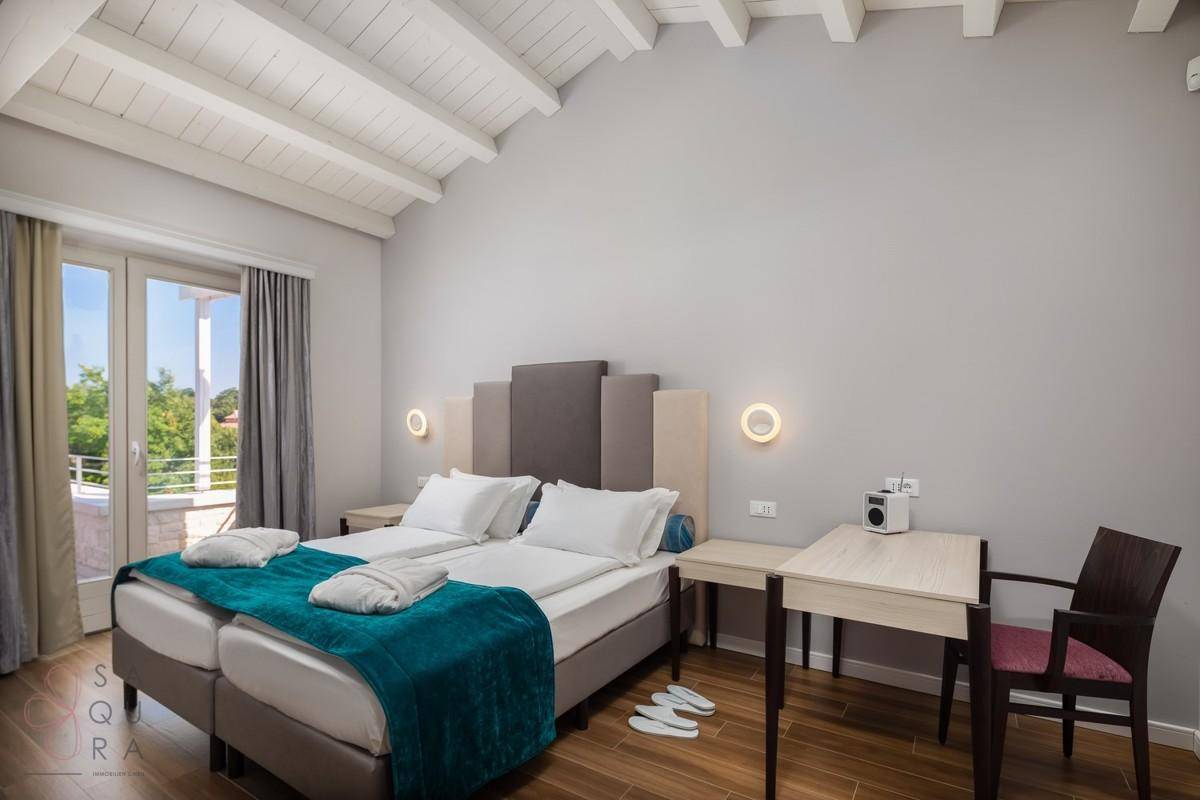 Schlafzimmer mit Holzbalkendecke, zwei Einzelbetten und direktem Zugang zu einem Balkon.