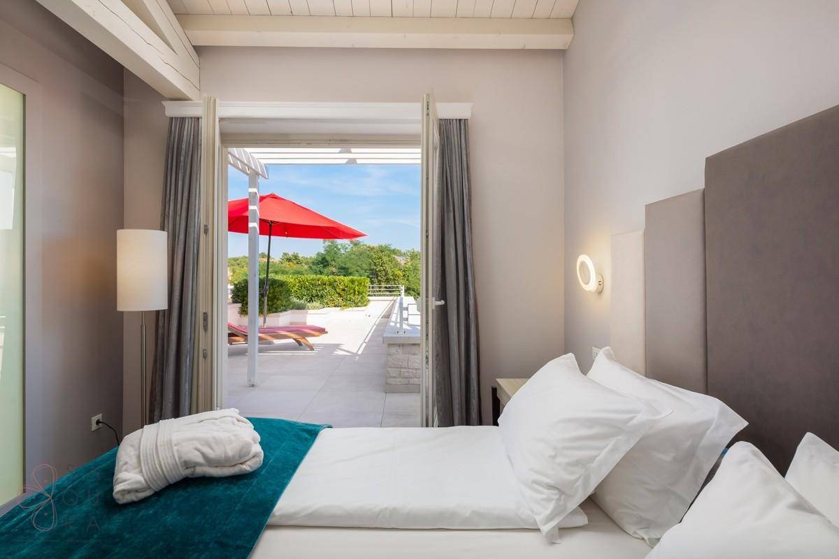 Schlafzimmer mit Holzbalkendecke, zwei Einzelbetten und direktem Zugang zur Terrasse.