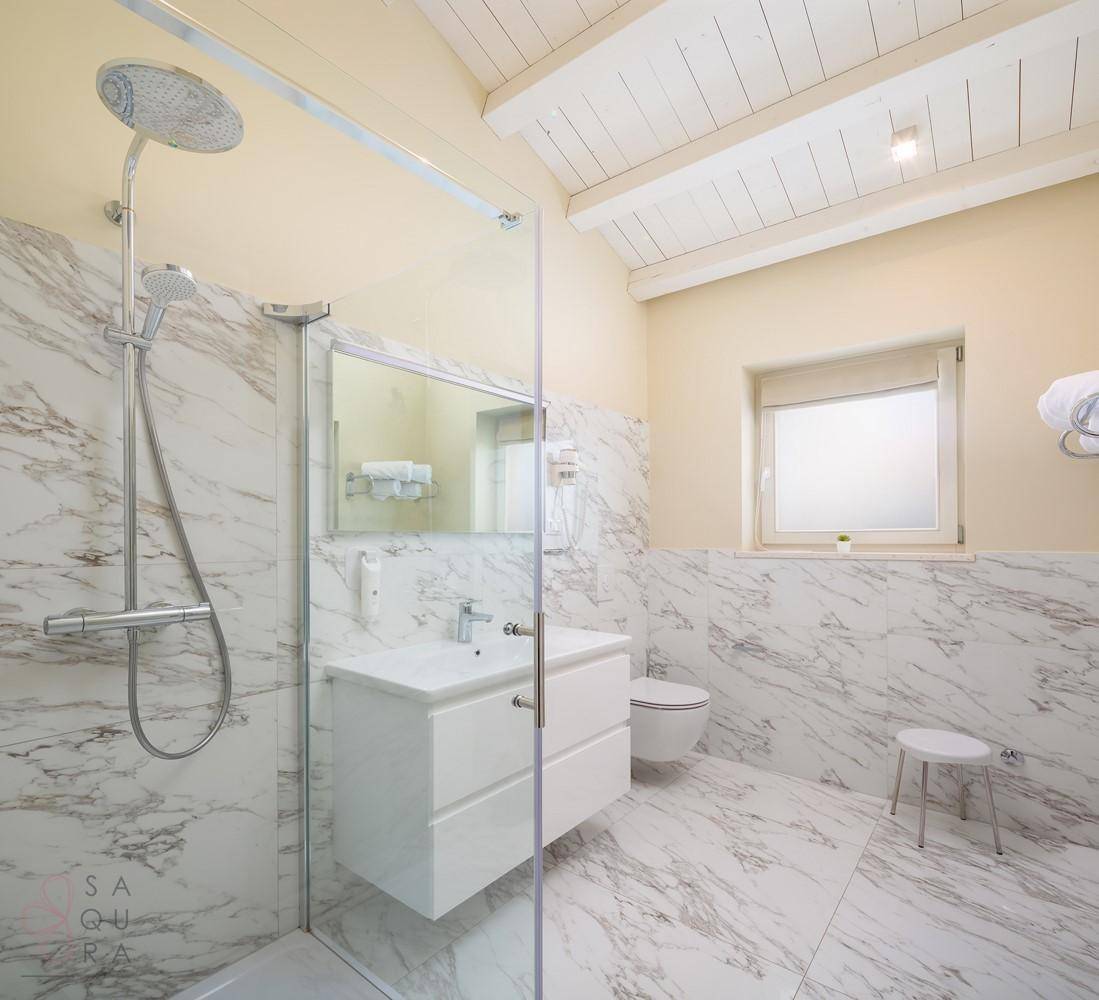 Modernes Badezimmer mit Marmorfliesen, Einzelwaschbecken und einer begehbaren Dusche mit Fenster.