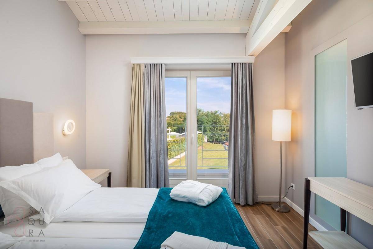 Gemütliches Schlafzimmer mit Balkonzugang, Holzbalkendecke und weitem Blick ins Grüne.