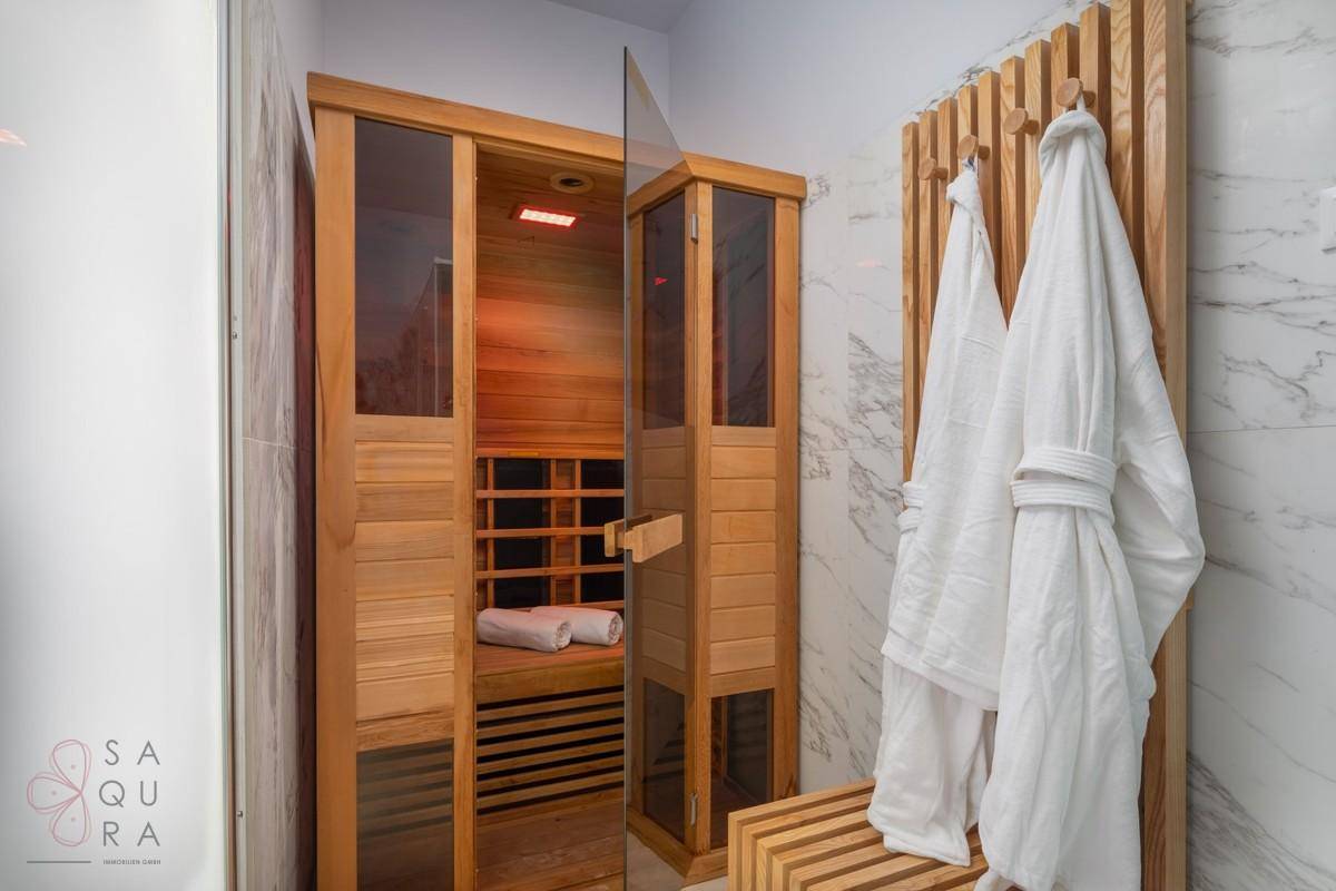 Wellnessbereich mit Holzsauna und Bademänteln, umgeben von Marmorfliesen.