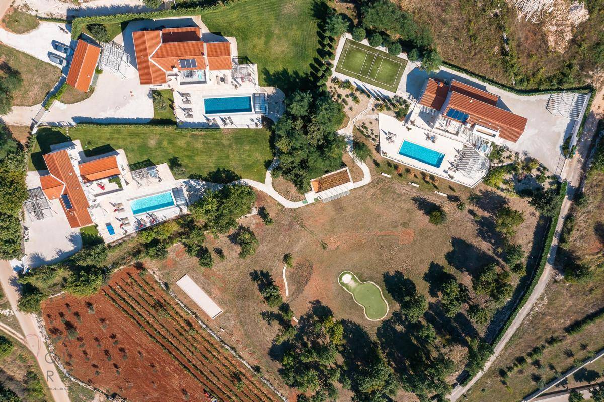 Überblick über das weitläufige Anwesen mit mehreren Villen, Pools, einem Tennisplatz und einem Golf-Putting-Green.
