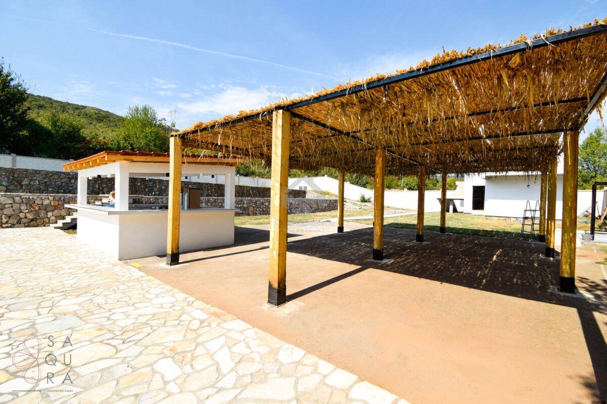 Überdachter Außenbereich mit einer Bar und einer Pergola mit Strohdach, ideal für Veranstaltungen.