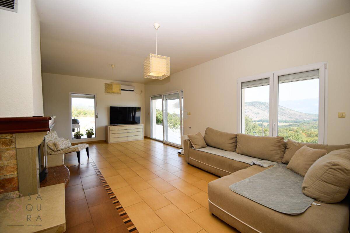 Helles Wohnzimmer mit Kamin, bequemer Couch und großen Fenstern mit weitem Ausblick.