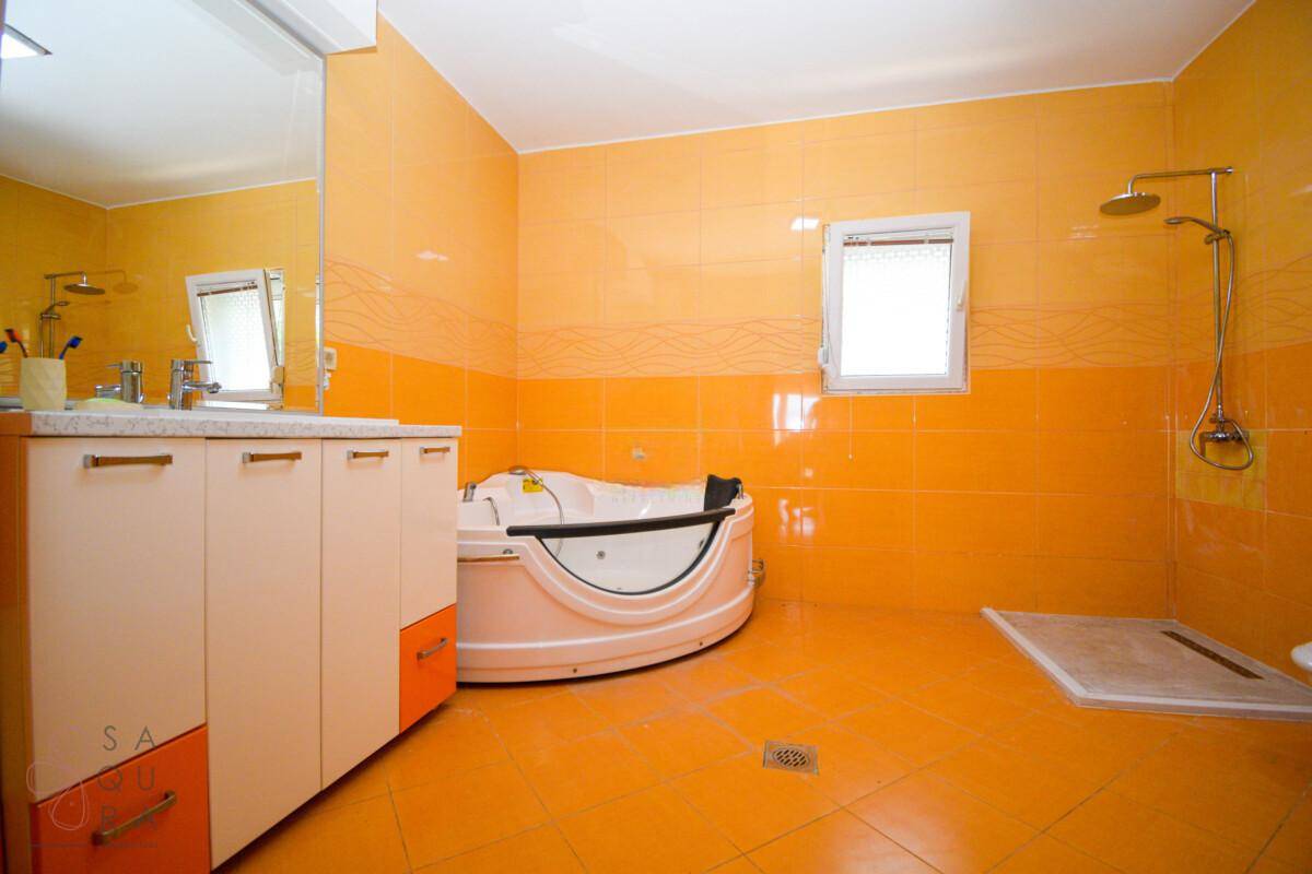 Modernes Badezimmer mit orangefarbenen Fliesen, Eck-Whirlpool und separatem Duschbereich.