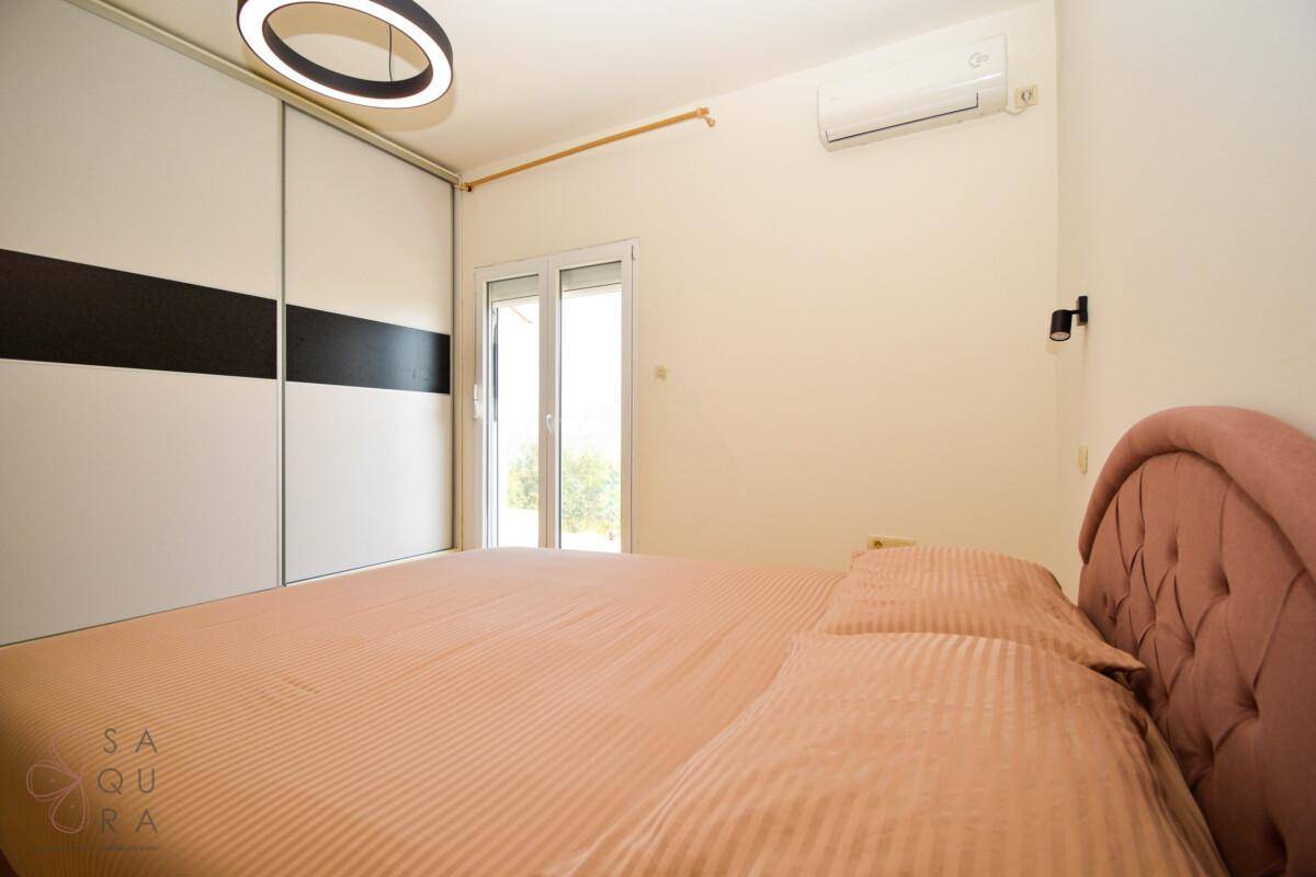 Schlafzimmer mit großem Bett, Schiebetürenschrank und Zugang zu einem Außenbereich.