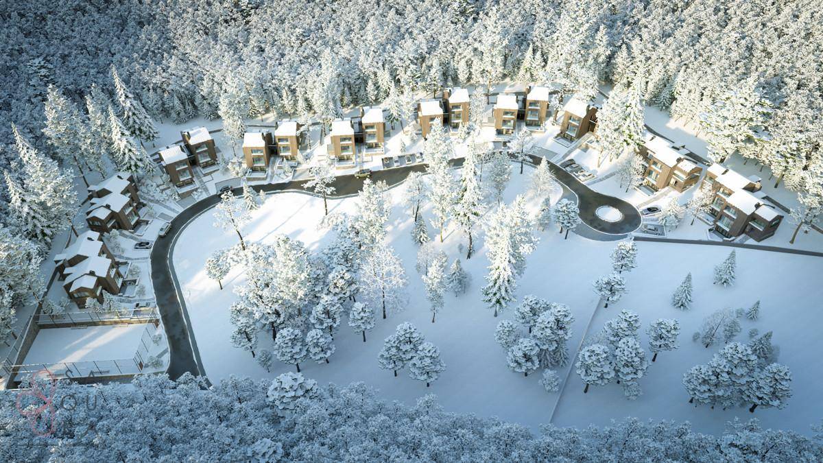 Luftaufnahme der modernen Wohnanlage in einer weitläufigen, verschneiten Waldlandschaft.