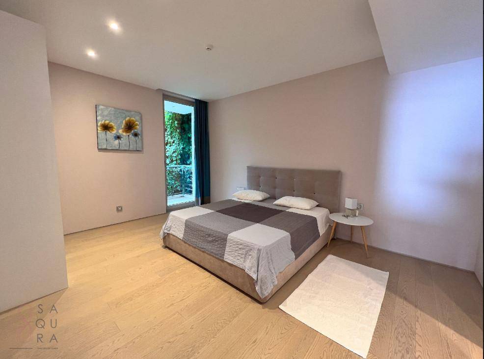 Gemütliches Schlafzimmer mit Doppelbett, Holzboden und Blick ins Grüne durch die Fenstertür.