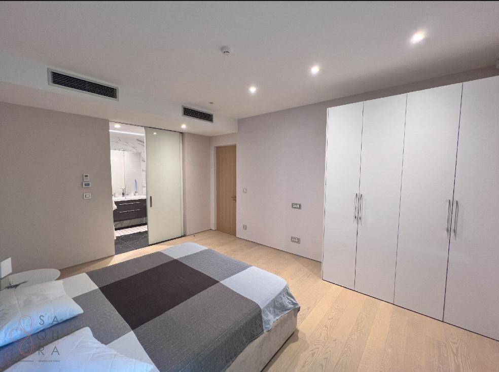 Schlafzimmer mit Schiebetür zum Badezimmer, Einbauschränken und Holzboden.